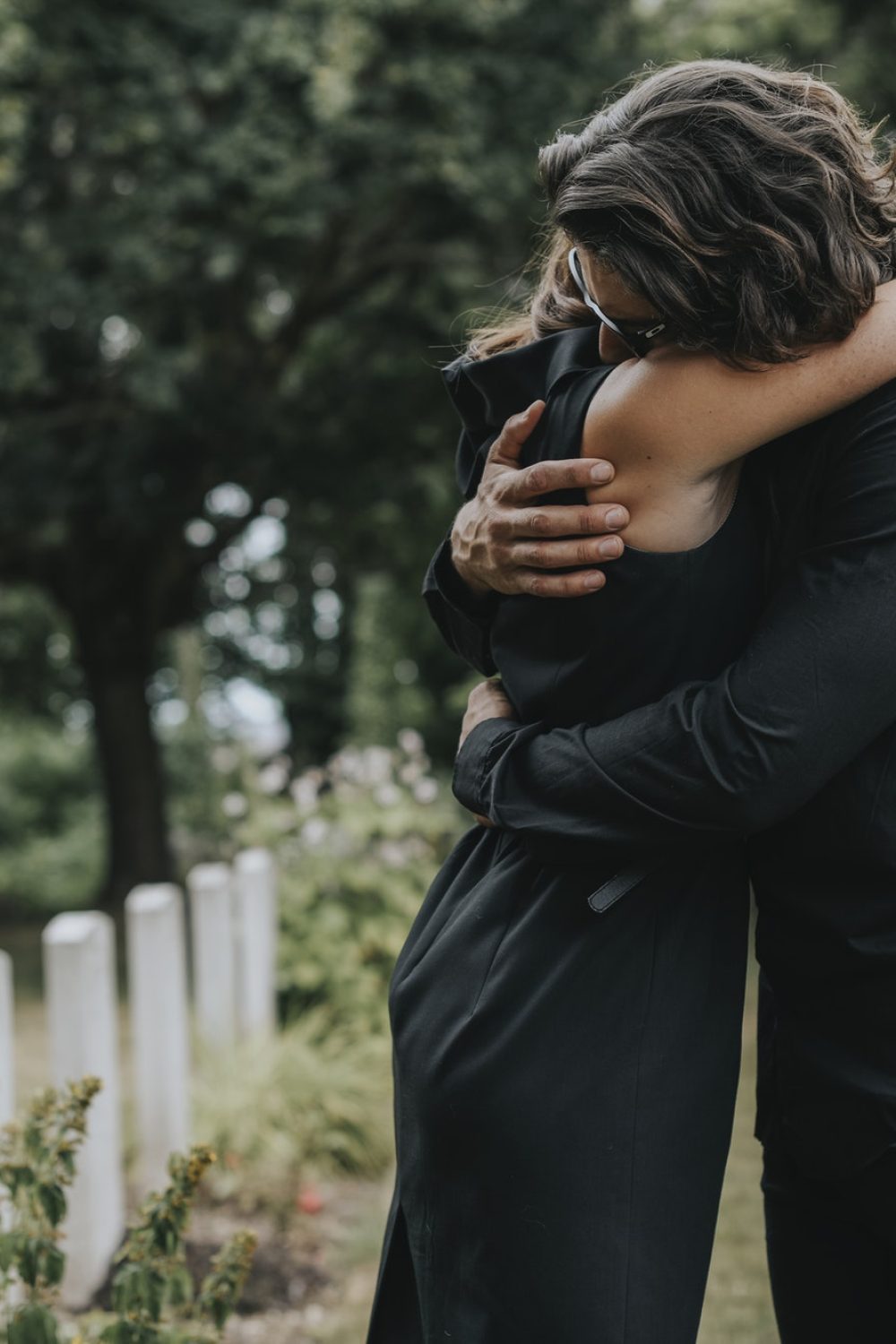 husband-trying-to-comfort-his-wife-at-a-graveyard.jpg